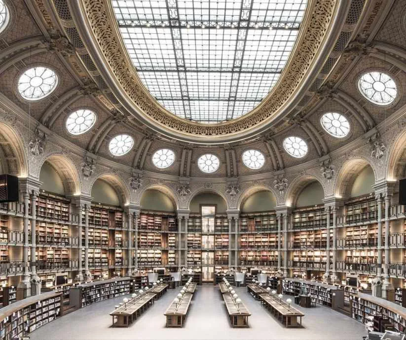 Interior de la Sala Oval de la Biblioteca Nacional de Francia, en París, con estanterías de libros, arcos ornamentados
