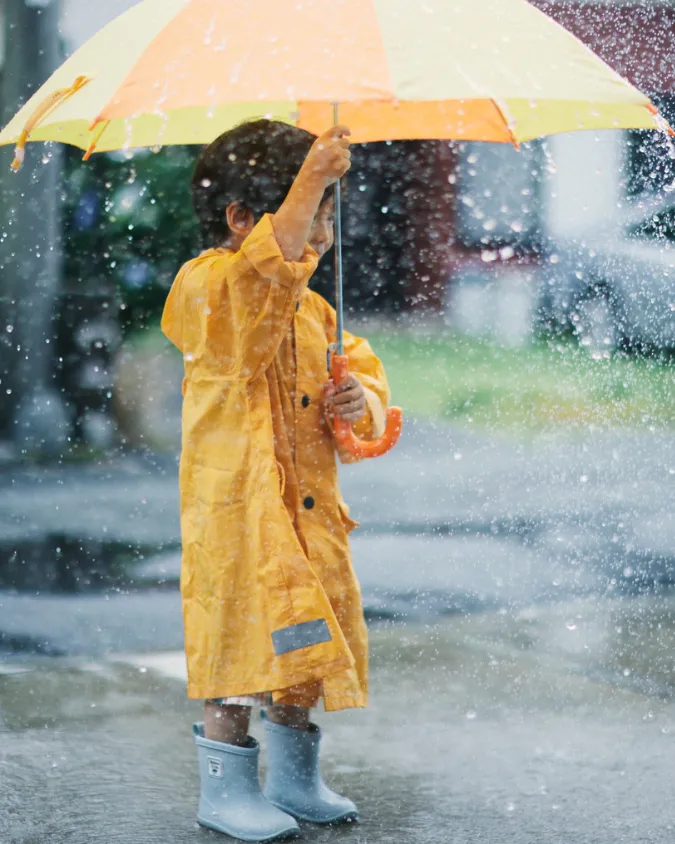 niño con sombrilla amarilla